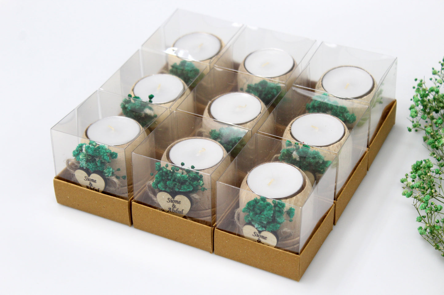 Set of nine personalized wooden candle holders featuring green floral arrangements, each elegantly packaged in a clear box. Ideal for weddings and special events, these handcrafted pieces include custom engraved tags with example names and dates. Perfect for adding a bespoke, rustic charm to any celebration