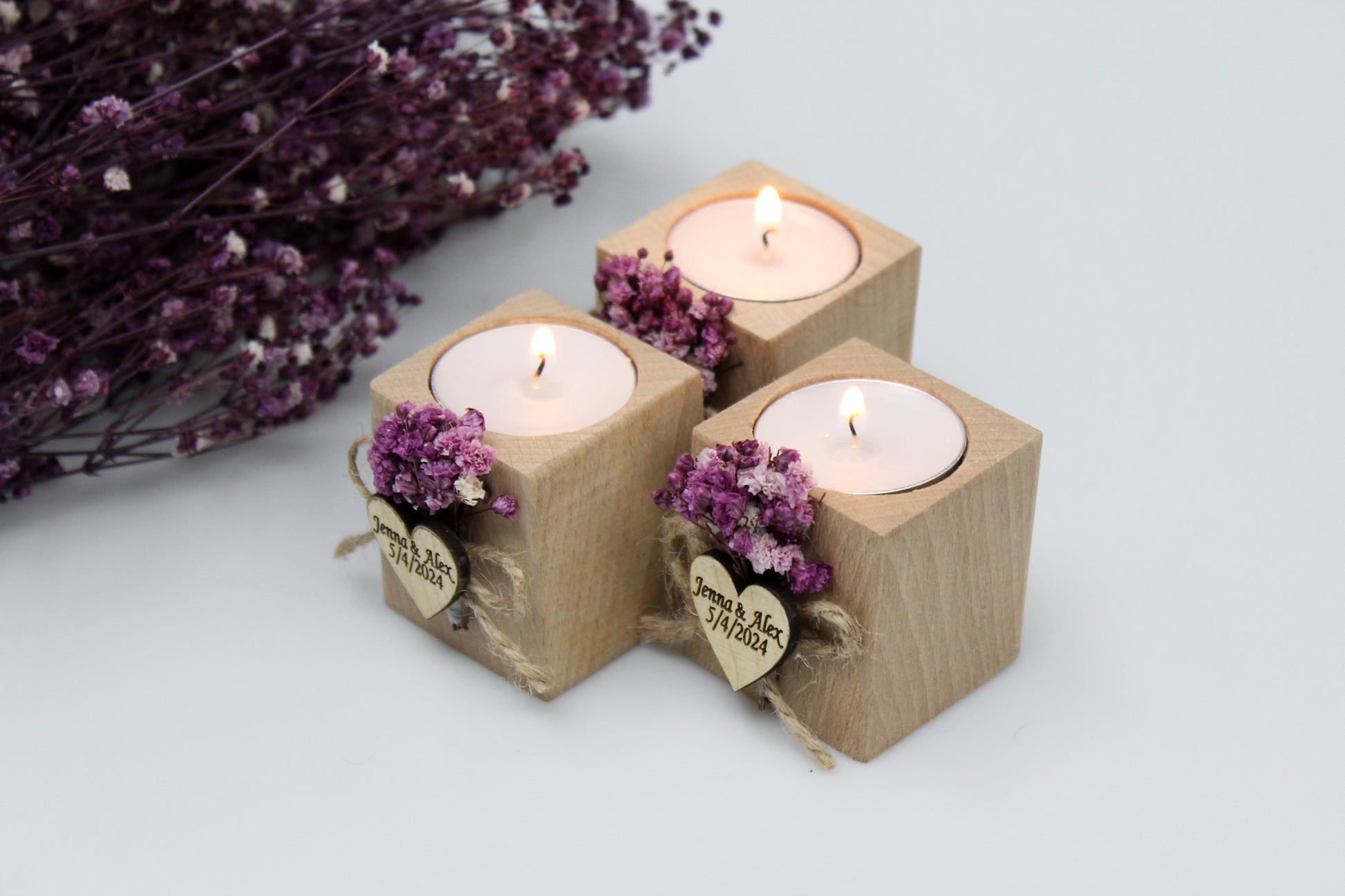 Personalized wooden candle holder wedding favors with purple dried flowers and customizable engraving, showcasing three lit candles, perfect for special occasions, with additional dried flowers in the background.