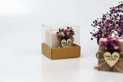 Personalized wooden candle holder wedding favor with purple dried flowers, featuring customizable names and date example 'Jenna & Alex 5/4/2024,' displayed in clear packaging. Another candle holder is partially visible in the background next to dried flowers.