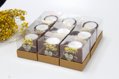 Set of elegant personalized wooden candle holders with yellow dried flowers, perfect for wedding favors. Each handcrafted piece features a heart-shaped tag engraved with example names 'Camille & Michael,' beautifully packaged in a transparent gift box. These rustic candle holders add a romantic touch to any celebration, ideal for enhancing wedding decor