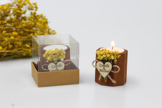 Elegant personalized wooden candle holder with yellow dried flowers, ideal for wedding favors. This handcrafted piece features a heart-shaped tag engraved with example names 'Camille & Michael,' making it a perfect rustic addition to wedding decor. Presented beautifully in a transparent gift box, this candle holder adds a touch of romantic charm to any celebration