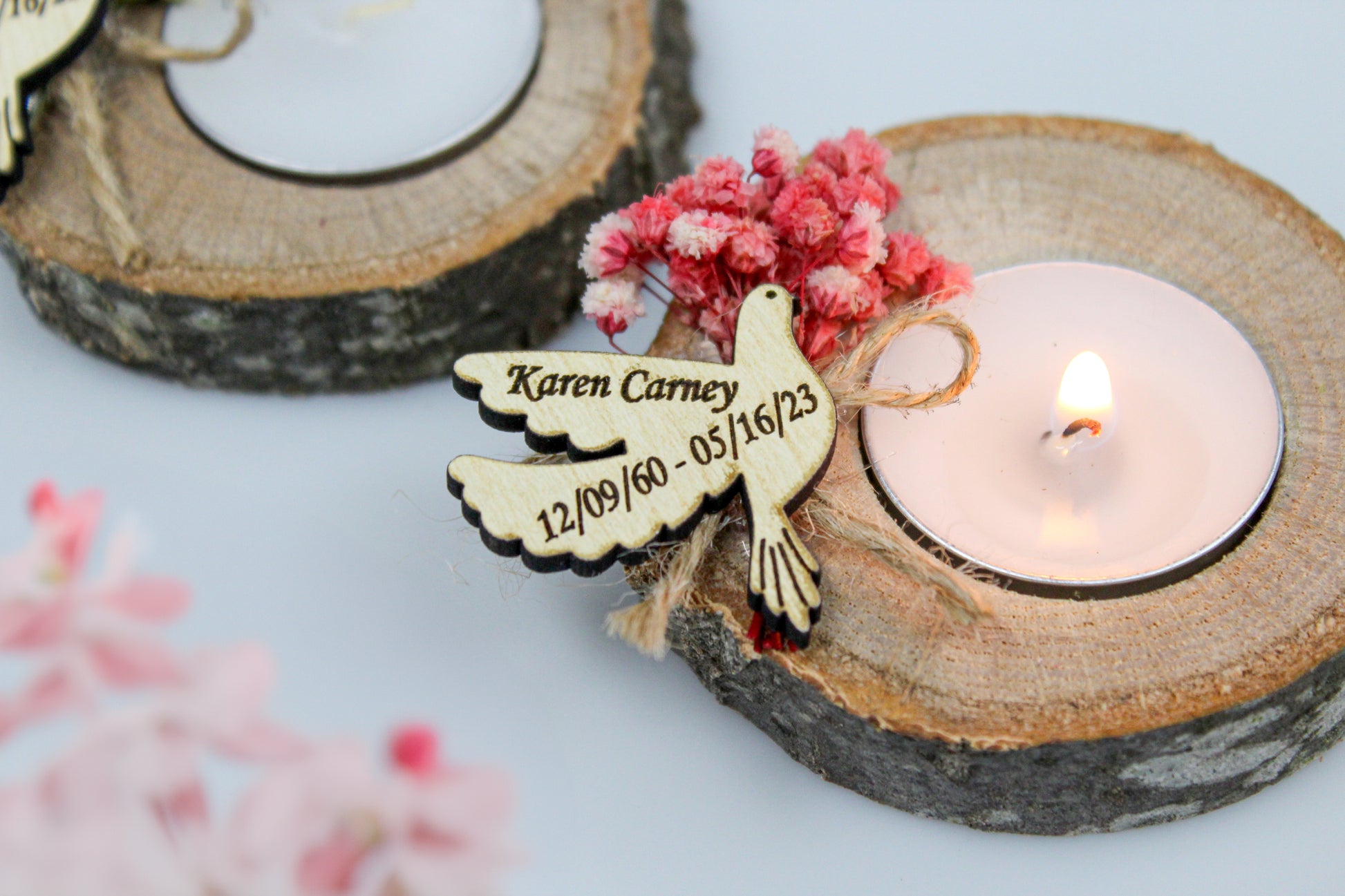 Exquisitely personalized handcrafted rustic memorial candle holder with an engraved dove tag, featuring the name "Karen Carney" and the dates "12/09/60 - 05/16/23". This elegant natural wood candle holder is adorned with delicate pink dried flowers, offering a unique and heartfelt funeral favor to honor and celebrate the cherished memory of a loved one.