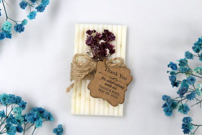 Exquisite personalized handmade wedding soap favor adorned with rustic twine and a custom thank you tag. This elegant soap favor features beautiful dried purple and white flowers, adding a charming and natural touch to your wedding celebration. Perfect for guests as a memorable keepsake from your special day.