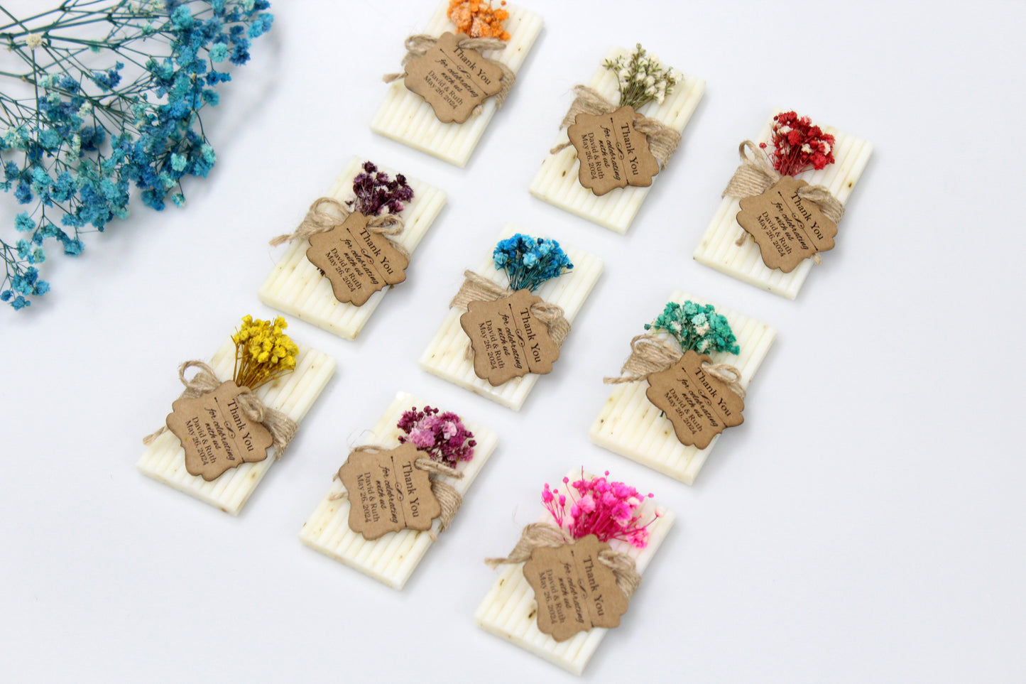 Beautifully personalized handmade wedding soap favors featuring a variety of dried flower arrangements in vibrant colors. Each soap is elegantly wrapped with rustic twine and a custom thank you tag, making these unique and charming keepsakes perfect for your wedding guests. Celebrate your special day with these exquisite and eco-friendly soap favors.