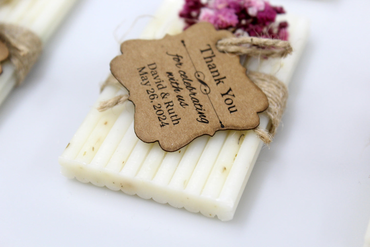 Close-up of a personalized handmade wedding soap favor, adorned with a rustic thank you tag and delicate purple dried flowers. Celebrate your special day with these beautifully crafted, eco-friendly wedding favors, offering a unique and memorable touch for your guests. Perfect for weddings, these handcrafted soaps serve as a charming and personalized keepsake