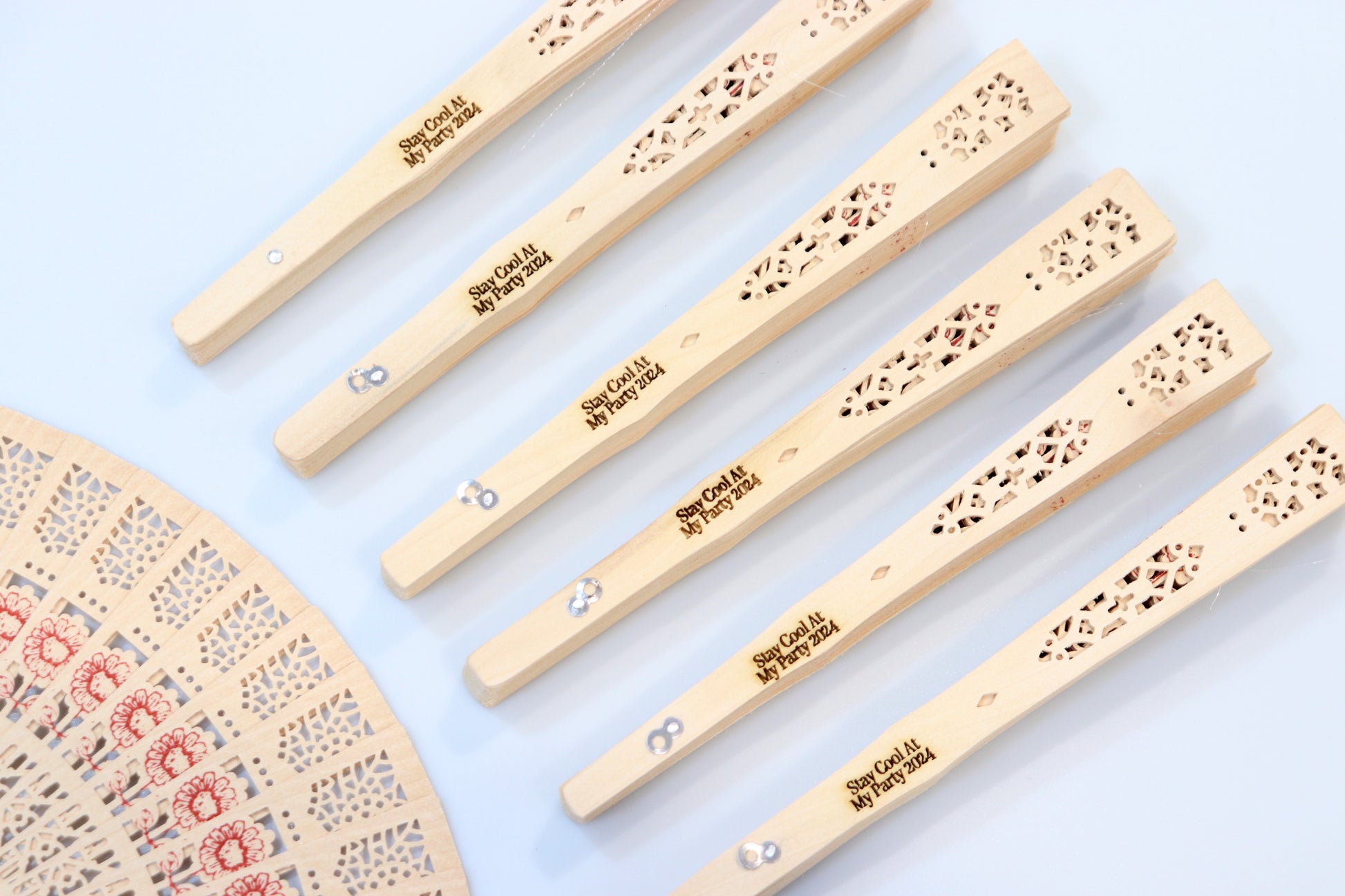 Custom engraved rustic wooden hand fans with intricate lace patterns, perfect for party favors, featuring personalized messages for guests.