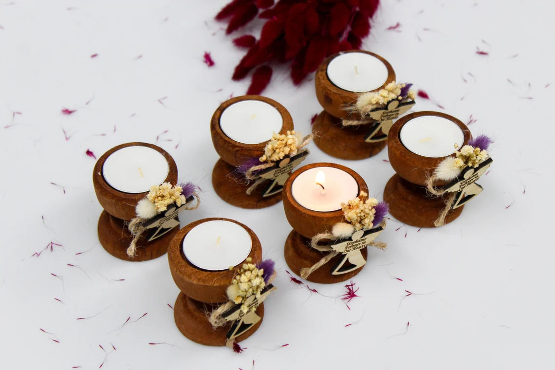 Set of personalized handcrafted funeral favor candle holders with 'Stephanie Forever in Our Hearts' engraved tags, featuring dried flowers in a rustic design. The candles are arranged in a serene display, with one candle lit in memory of Stephanie.